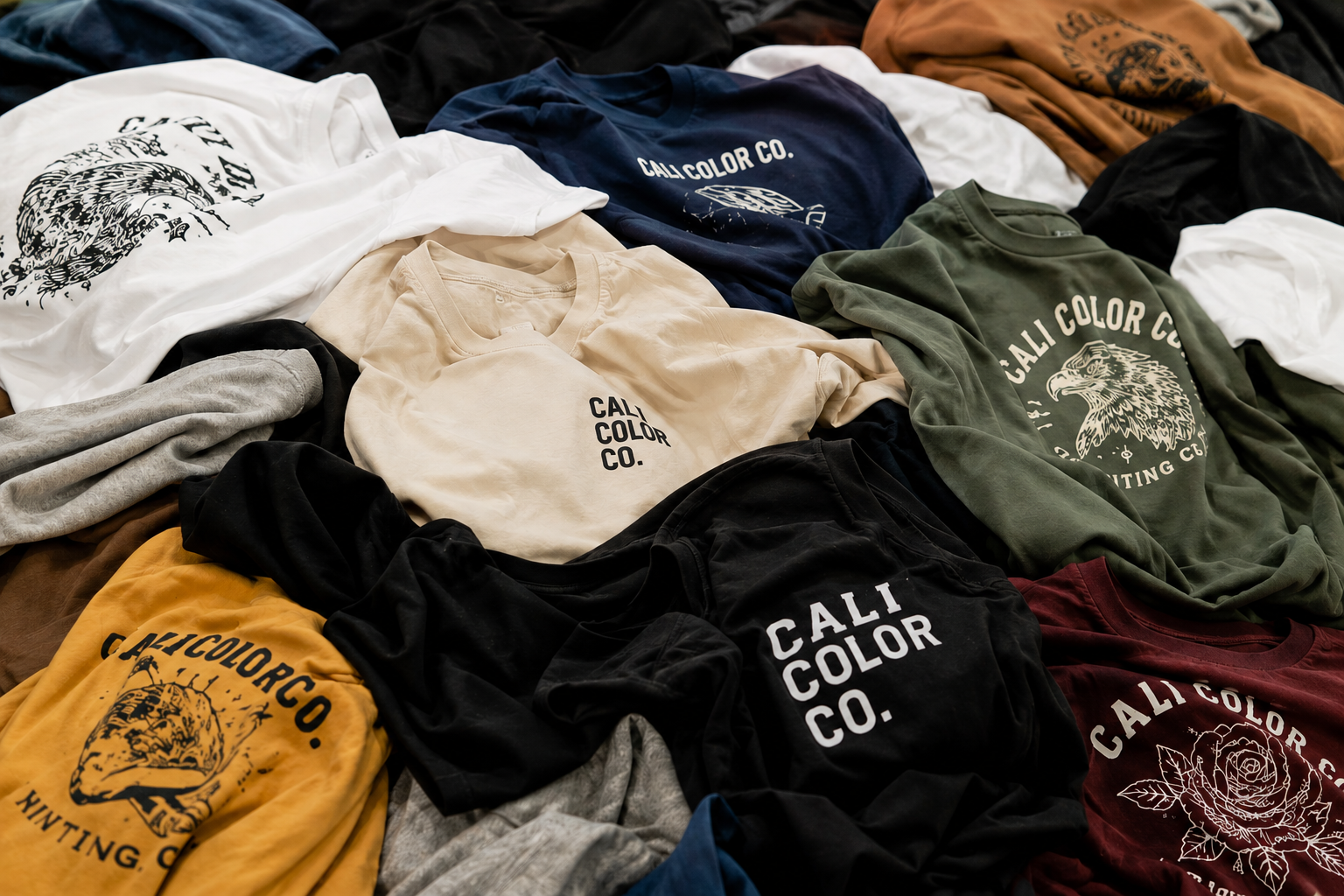 Assorted Cali Color Co custom printed apparel in a pile